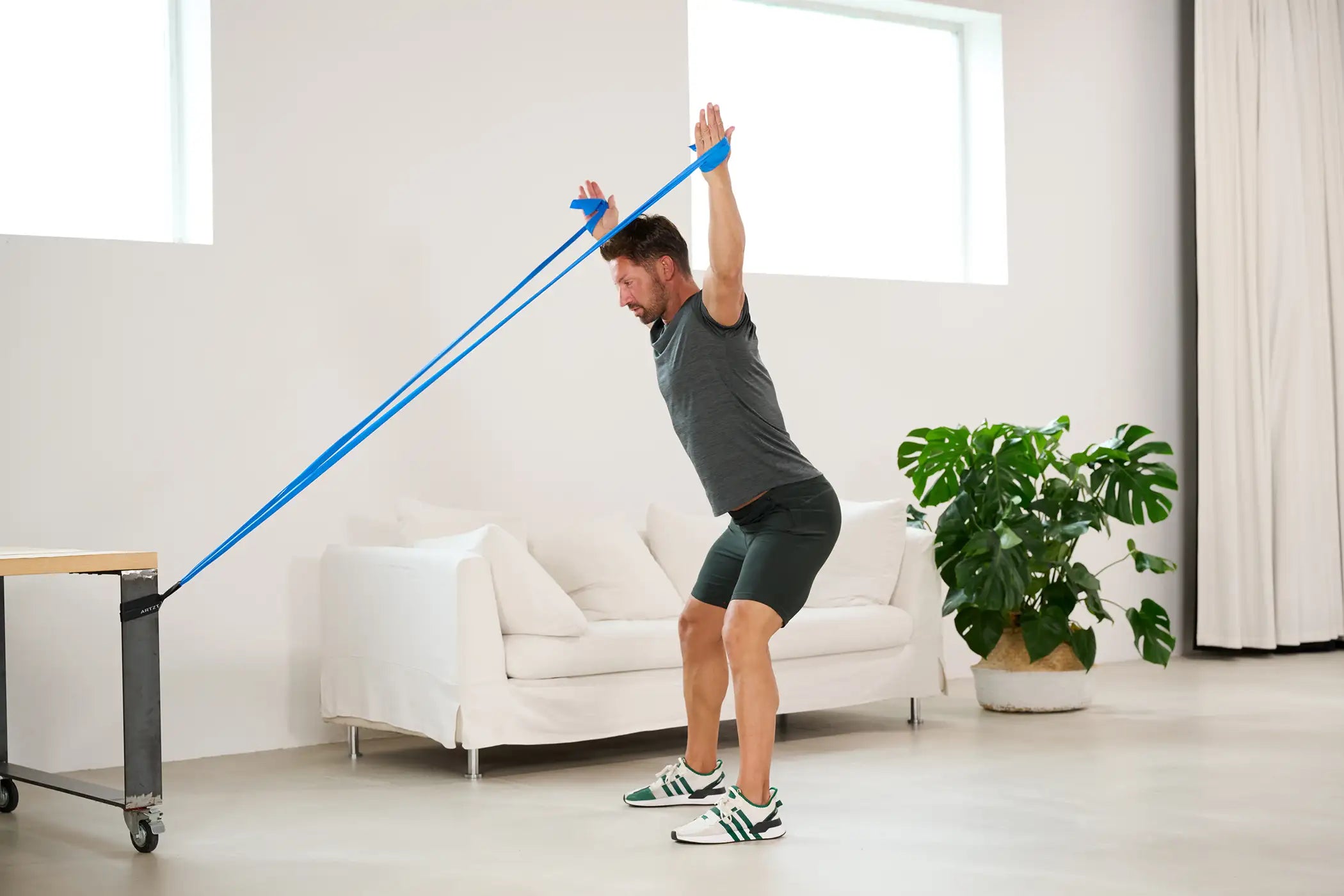 Mann trainiert seine hintere Schultermuskulatur mit einem ARTZT vitality Fitnessband.