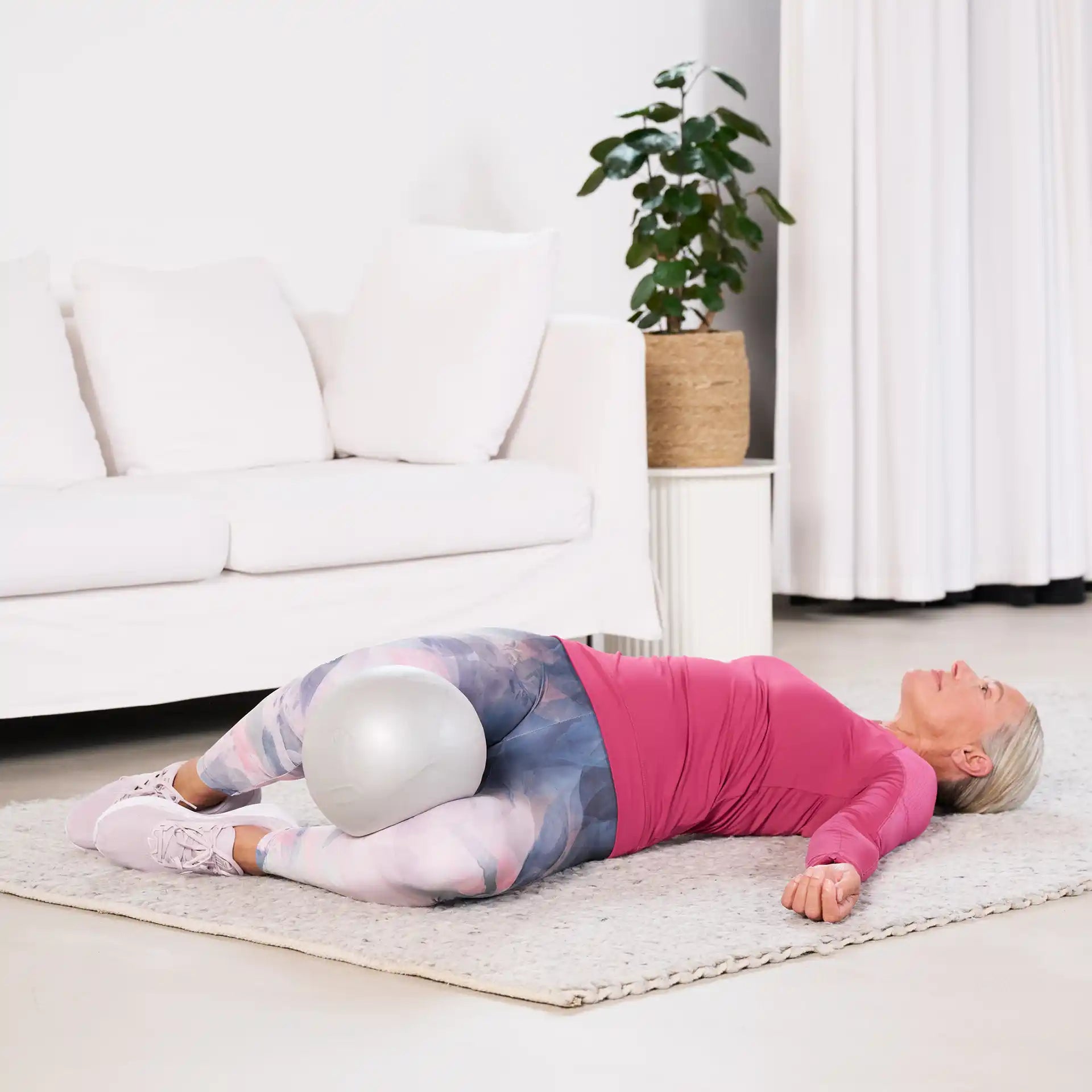 Bestager trainiert mit ARTZT vitality Pilates Ball im Wohnzimmer