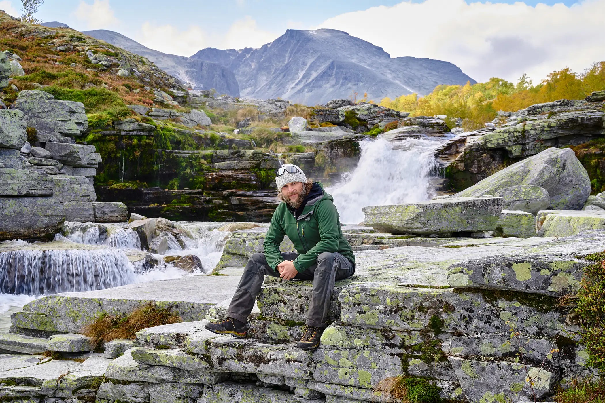 Felix Artzt sitzt in Island vor einem Wasserfall.